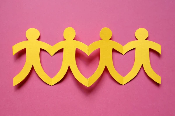 Teamwork, gelbe Papiermenschen auf rosa Hintergrund — Stockfoto