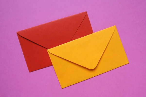 Envelopes vermelho e laranja sobre fundo rosa — Fotografia de Stock