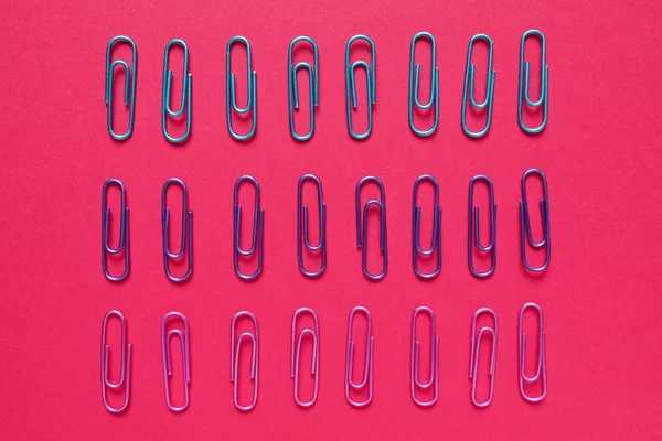 Plano poner composición regular de clips de papel de colores sobre fondo rosa — Foto de Stock