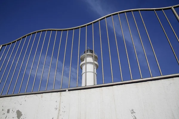 Faro blanco detrás de barrera metálica — Foto de Stock