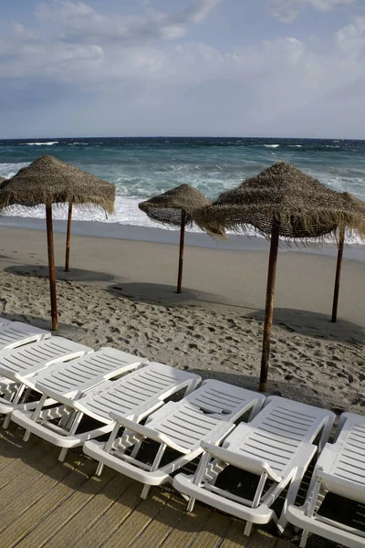 Lege strand met stro parasols en strandstoelen — Stockfoto