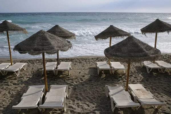 Plage vide avec parasols en paille et chaises longues — Photo