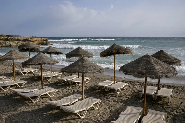 Playa vacía con sombrillas de paja y silla de playa —  Fotos de Stock