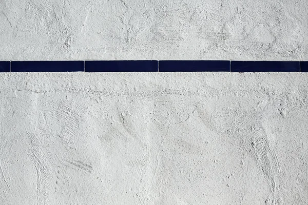 Witte muur met strip van blauwe tegels — Stockfoto