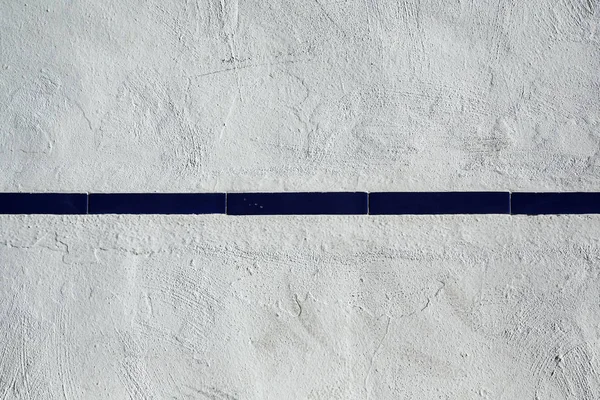 Witte muur met strip van blauwe tegels — Stockfoto