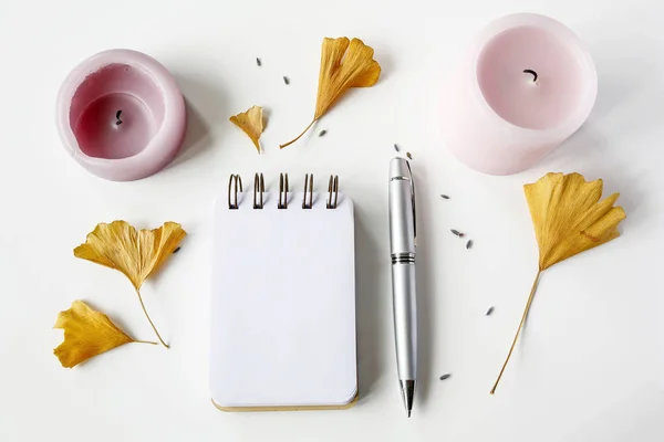 Caderno, caneta, velas, folhas de ginkgo na mesa branca — Fotografia de Stock