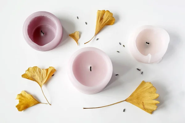 Composición laica plana de velas de color rosa, hojas de gingko y semillas de lavanda en la mesa blanca —  Fotos de Stock