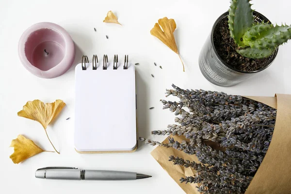 Caderno, caneta, velas, folhas de ginkgo, lavanda, cacto sobre mesa branca — Fotografia de Stock