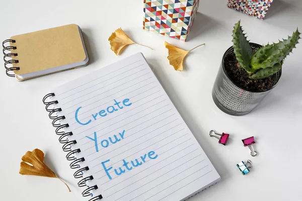 Crea tu futuro escrito en un cuaderno sobre una mesa blanca — Foto de Stock