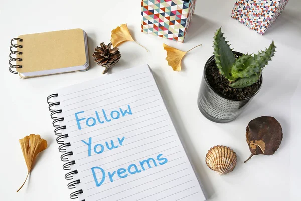 Podążaj za swoimi marzeniami, zapisane w notesie na biały stół — Zdjęcie stockowe