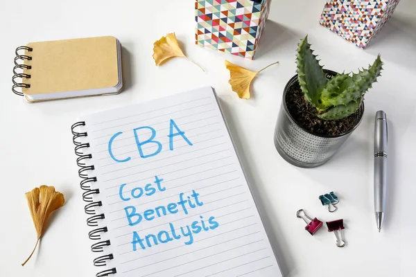 CBA- Análisis de los costes que ofrecen los beneficios escritos en un cuaderno sobre una mesa blanca — Foto de Stock
