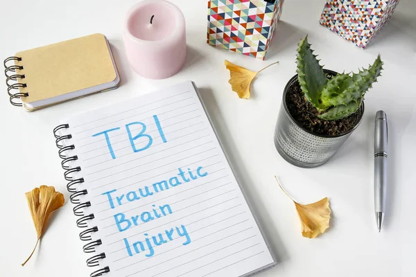 TBI Traumatic Brain Injury written in notebook on white table