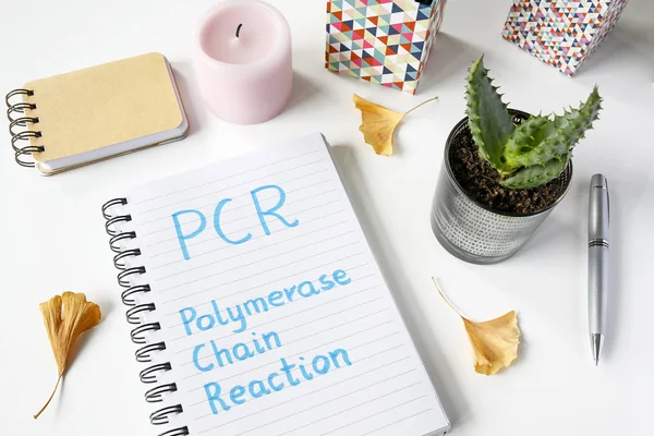 PCR Polymerase Chain Reaction written in notebook on white table