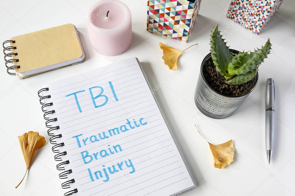 TBI Traumatic Brain Injury written in notebook on white table