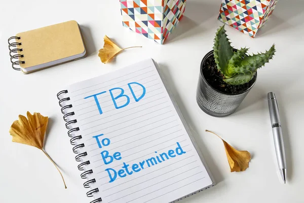 TBD A Determinar Escrito en un cuaderno sobre mesa blanca — Foto de Stock