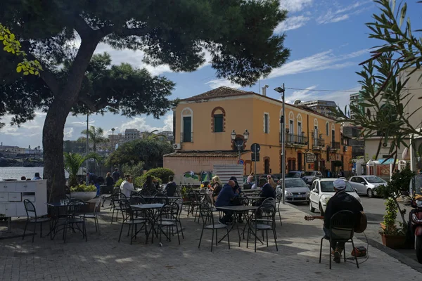 Catania, Sicilia, Italia - 9 novembre 2019: gente del posto indefinita e turista che si rilassa in un bel caffè all'aperto vicino al porto turistico e al molo di San Giovanni Li Cuti a Catania nella giornata di sole . — Foto Stock