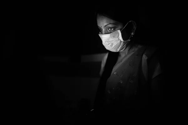 Young indian Woman wearing mask working on her laptop late night, freelancer working from home. Coronavirus,Covid-19. stay home stay safe, woman in quarantine.