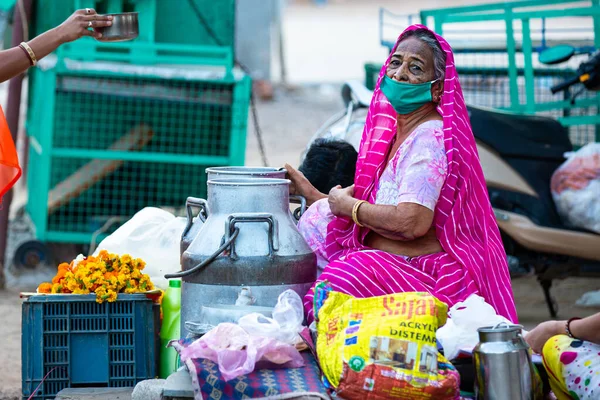 Jodhpur, Rajashtbn, Hindistan. 30 Mart 2020. Korumalı maske takan yaşlı bir kadın, Hindistan 'da Coronavirus, COVID-19 salgını yüzünden yolda yiyecek satıyor..