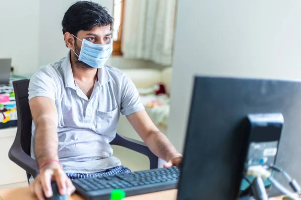 Young man quarantined at home during World Pandemic of Coronavirus Covid-19 prevention. Stay at home, stay safe. man with protective medical mask using computer. isolation, lock down situation.