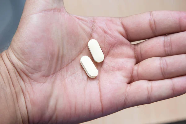 Sıtma tedavisi için hidrokloroksin tableti ve COVID 19 Corona virüsü için potansiyel yeni ilaç tedavisi. Coronavirus tedavisi. Ahşap masanın üzerinde ilaç var. Tablet elinde..
