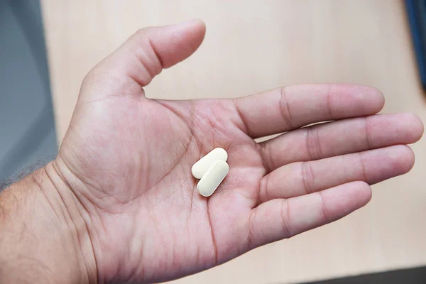 Sıtma tedavisi için hidrokloroksin tableti ve COVID 19 Corona virüsü için potansiyel yeni ilaç tedavisi. Coronavirus tedavisi. Ahşap masanın üzerinde ilaç var. Tablet elinde..