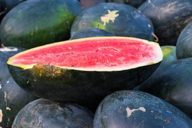 Olgun karpuz yığını üzerinde kırmızı kesilmiş karpuz, yaz sulu meyve. 
