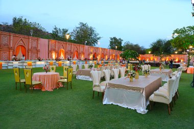 Jodhpur, Rajasthan, Hindistan - 18 Mayıs 2018: Lüks yemek masaları ve sandalyeler, bahçedeki çiçeklerle süslenmiş, Hint düğün düzenlemeleri - görüntü