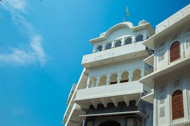 Mavi gökyüzüne karşı birçok ahşap kapı ve penceresi olan beyaz bir binanın geleneksel ev mimarisi, binanın ön cephesinin mimari bir unsuru