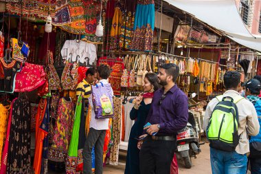 Puşkar, Rajasthan, Hindistan - 14 Kasım 2019: Hintli çift yerel pazarda geleneksel Hint tarzı kıyafet dükkanı satın alıyor.