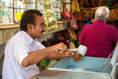 Mumbai, Rajasthan, Hindistan - 18 Haziran 2019: Hintli adam yerel sokak pazarında kilden yapılmış bir bardak Lassi veya milk shake doldurup satıyor. Yaz içeceği.