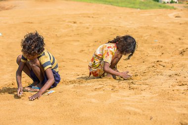 Jodhpur, Rajasthan, Hindistan - 18 Haziran 2019: Sıcak yazda kumla oynayan fakir kırsal çocuklar, imtiyazsız Hintli çocuklar.