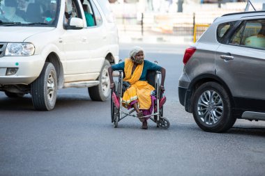 Jodhpur, Rajasthan, Hindistan - 20 Mayıs 2020: Tekerlekli sandalyede oturan, maske takan zavallı, engelli yaşlı kadın, tecrit krizi sırasında yolda geziniyor, yiyecek bir şey yok, gidecek yer yok.