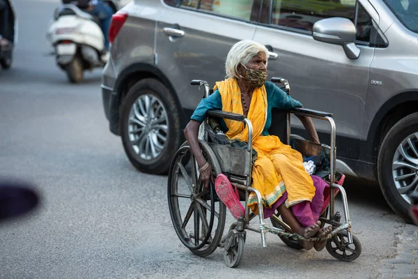Jodhpur, Rajasthan, Hindistan - 20 Mayıs 2020: Tekerlekli sandalyede oturan, maske takan zavallı, engelli yaşlı kadın, tecrit krizi sırasında yolda geziniyor, yiyecek bir şey yok, gidecek yer yok.