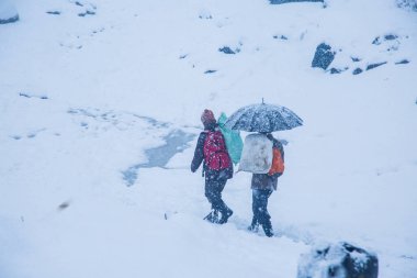 Himachal 'da karlı bir günde şemsiyeli iki adam yürüyor. Karlı kış konsepti, geniş açı çekimi - Görüntü