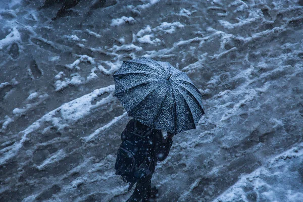 冬雪飘落 一个人带着黑色的雨伞走在路上 背景图片 — 图库照片