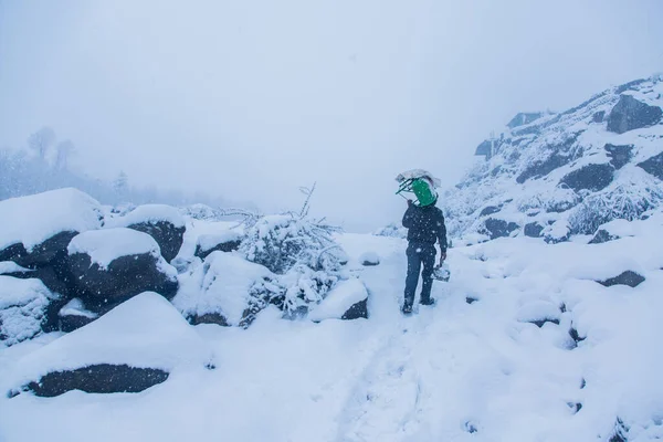 Mężczyzna Chodzący Ciężkim Śniegu Podnosząc Zielony Piec Ramieniu Dziwne Warunki — Zdjęcie stockowe