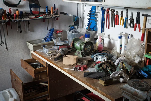 Messy workshop, complete chaos on workbench, unorganised basement or garage. Efficiency and arrangement in workshop, time to sort out mess concept.