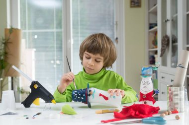 Küçük çocuk yoğurt şişe ve kağıt ev yapımı-it-yourself oyuncakların yapma yaratıcı olmak. Destekleyici yaratıcılık, yaparak, el el sanatları öğrenme. Görme yaratıcı bir şekilde erişim çocuğa yardım.
