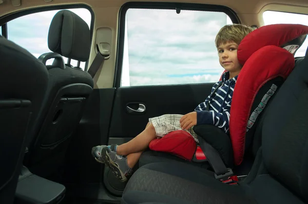 Little boy sitting in high back booster car seat fasten with seat belt. Child safety.