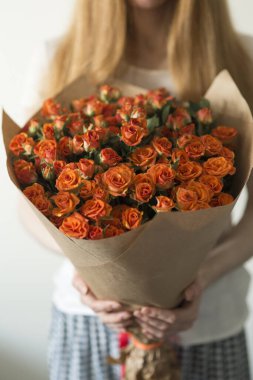 Turuncu eli tutan turuncu kız, elinde çiçekler. Çiçek buketini tut