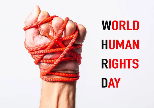 เชือกสีแดงบนกําปั้นมือกับโลก HUMAN RIGHTS วันข้อความบนสีขาว — ภาพถ่ายสต็อก