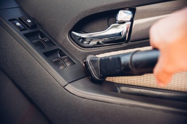 İşçi adam arabanın içindeki tozları temizliyor.