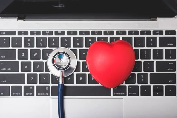 Gesundheitsstethoskop und rotes Herz auf der Tastatur des Laptops — Stockfoto