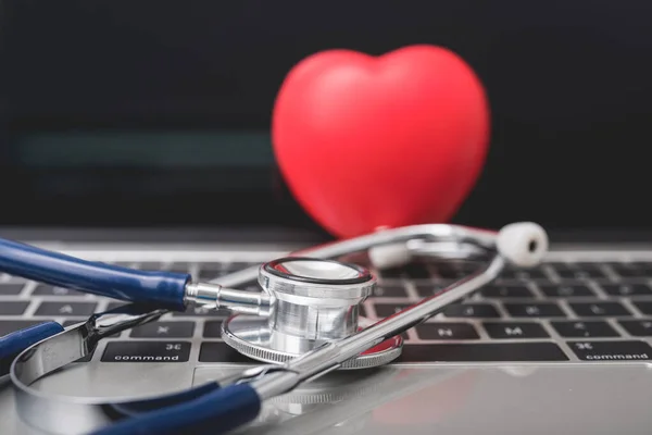 Gesundheitsstethoskop und rotes Herz auf der Tastatur des Laptops — Stockfoto