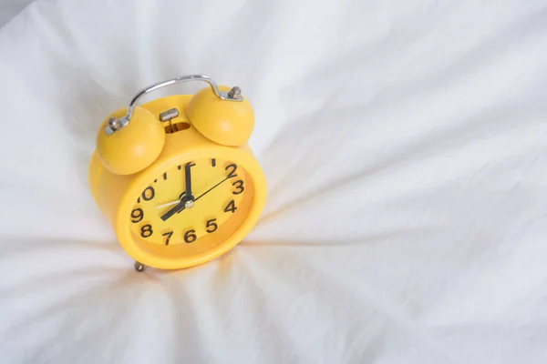 Relógio de alarme amarelo às 8 da manhã na cama — Fotografia de Stock