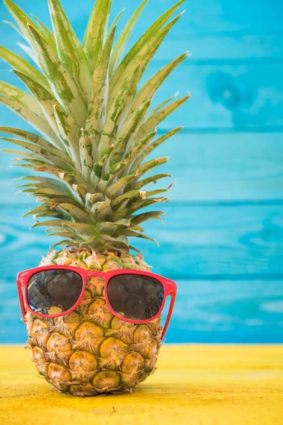 Праздничные ананасы в солнечных очках на синем деревянном фоне — стоковое фото