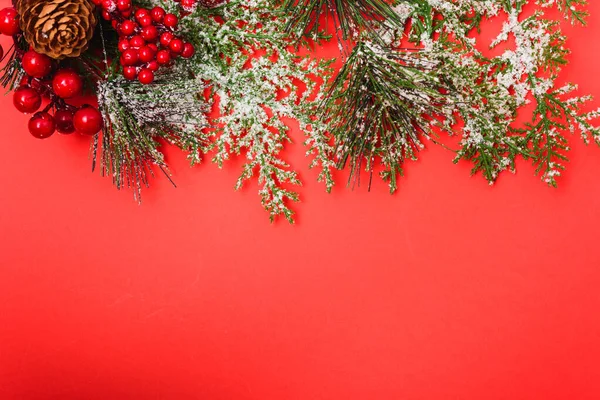 Noel süslemeleri, kırmızı arka planda köknar dalları. — Stok fotoğraf
