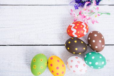 Paskalya yumurtaları beyaz ahşap zemin üzerinde üst görünüm ve kullanım için çalışma alanı tahtası