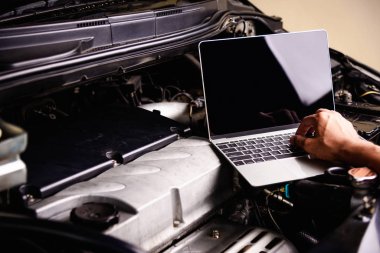 Atölyede dizüstü bilgisayarla çalışan profesyonel araba tamiri ya da bakım motoru servisi