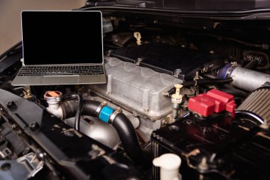 Atölyedeki servis için araba tamircisi motorundaki dizüstü bilgisayar
